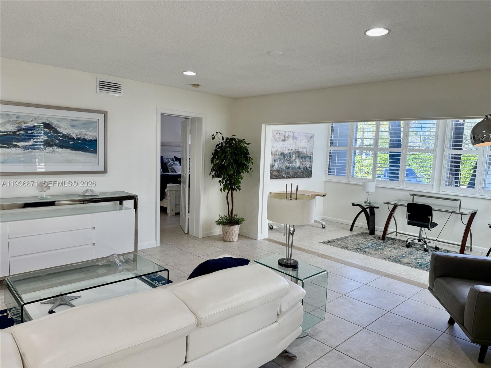 A living room features white tile flooring, a white sofa, and an adjacent office area — 4161 S Us Highway 1 # K1, Jupiter FL 33477, JUPITER, FL
