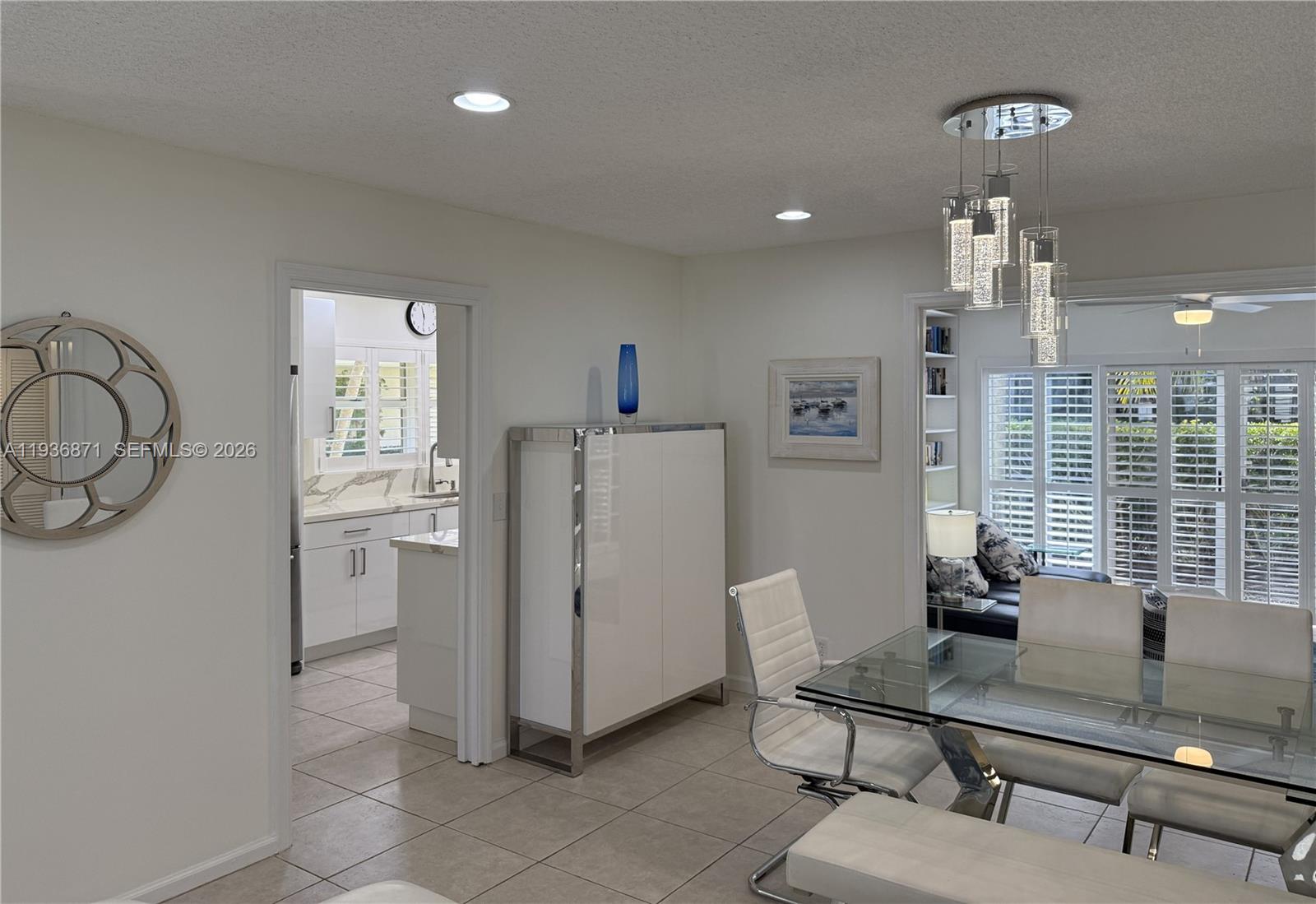 A dining area with a glass table and modern chandelier leads into a white kitchen — 4161 S Us Highway 1 # K1, Jupiter FL 33477, JUPITER, FL
