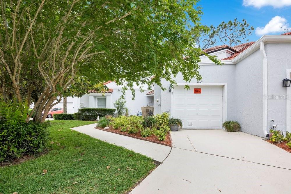 A white garage door is attached to a light-colored house with a landscaped front yard — 2604 ALBION AVENUE, ORLANDO, FL