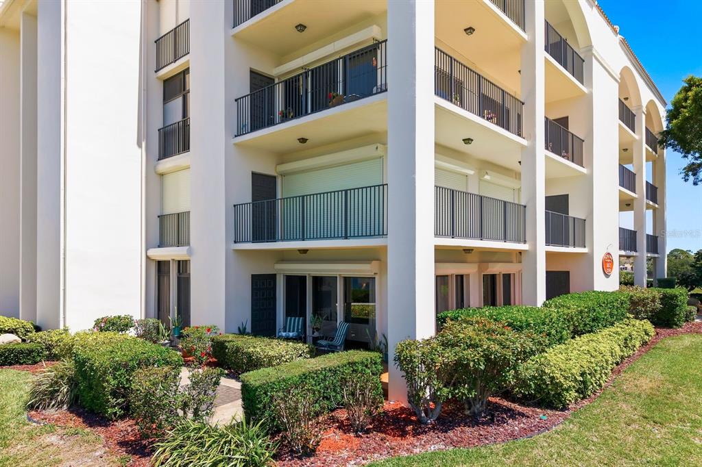 A multi-story apartment building features balconies with black railings and ground-level patio access — 302 MARINER DRIVE UNIT 302, TARPON SPRINGS, FL