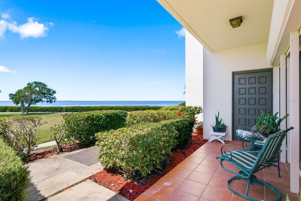 A tiled patio features a green chair, a small plant, and a view of the water — 302 MARINER DRIVE UNIT 302, TARPON SPRINGS, FL