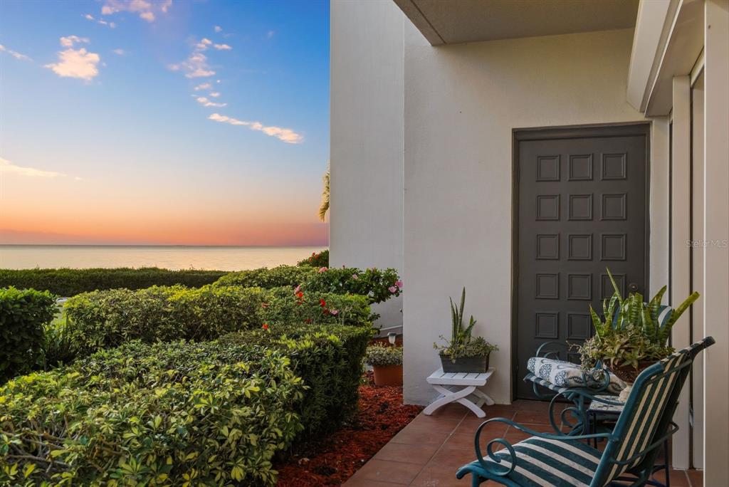 A patio with tiled flooring, outdoor chairs, and a view of the ocean at sunset — 302 MARINER DRIVE UNIT 302, TARPON SPRINGS, FL