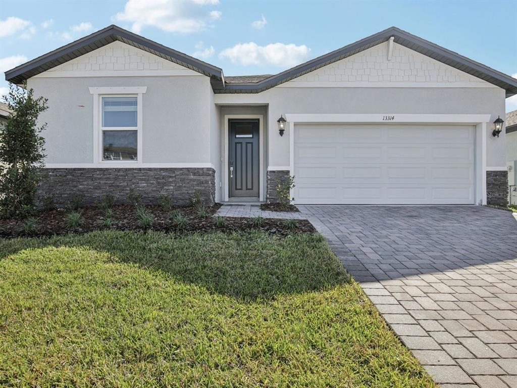 A single-story house features a gray stucco exterior, stone veneer base, and a paved driveway — 13314 SHELLMORE AVENUE, PALMETTO, FL