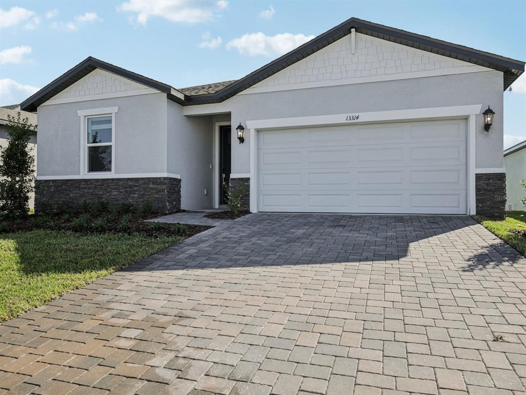 A single-story house with a gray stucco exterior, stone veneer base, and a paved driveway — 13314 SHELLMORE AVENUE, PALMETTO, FL