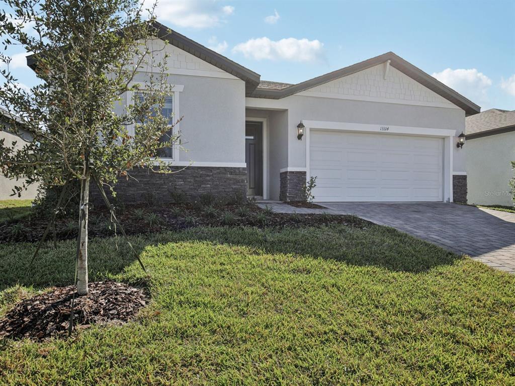 A single-story house with a gray stucco exterior, stone accents, and a two-car garage — 13314 SHELLMORE AVENUE, PALMETTO, FL