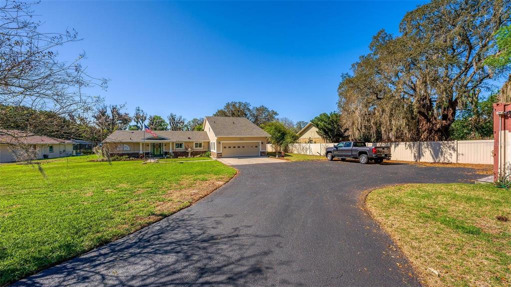 An aerial view shows a house with a screened-in pool, a long driveway, and surrounding lawn — 10220 BUMBLEBEE LANE, LEESBURG, FL