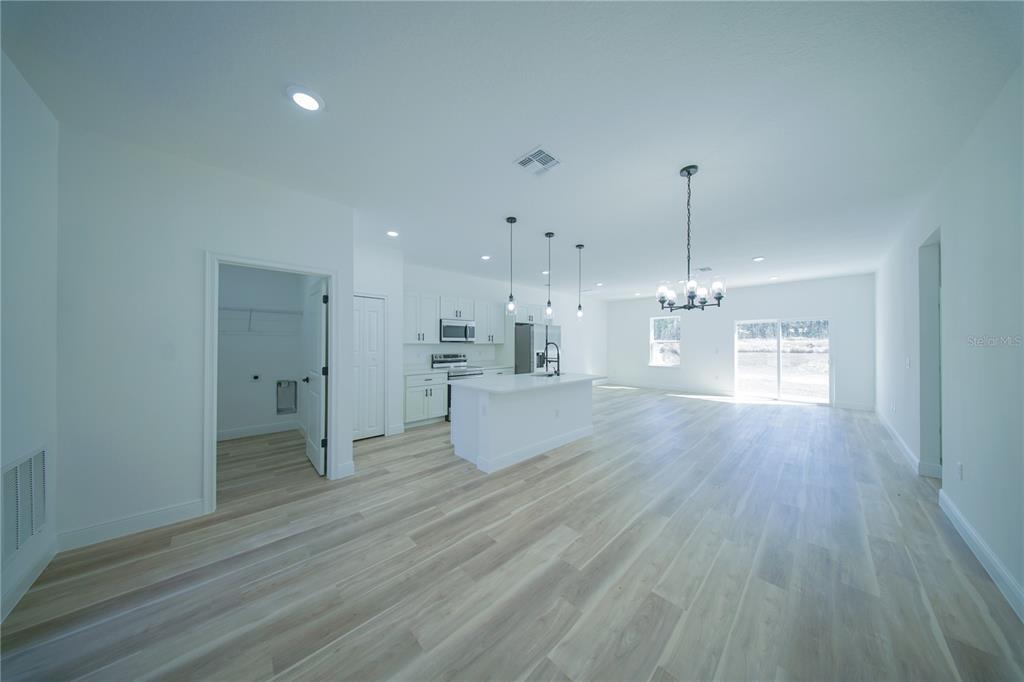 A bright, open-concept kitchen and living area features white cabinetry, a central island, and light-colored flooring — 13753 SW 79TH TERRACE ROAD, OCALA, FL