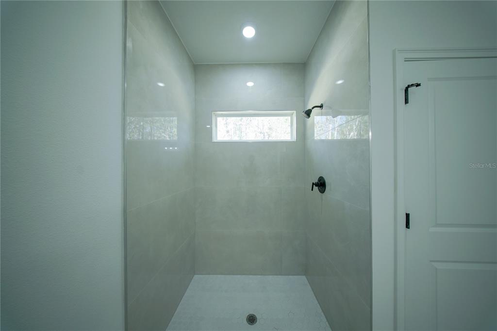 A walk-in shower features light-colored wall tiles, a hexagonal floor tile, and a small window — 13753 SW 79TH TERRACE ROAD, OCALA, FL