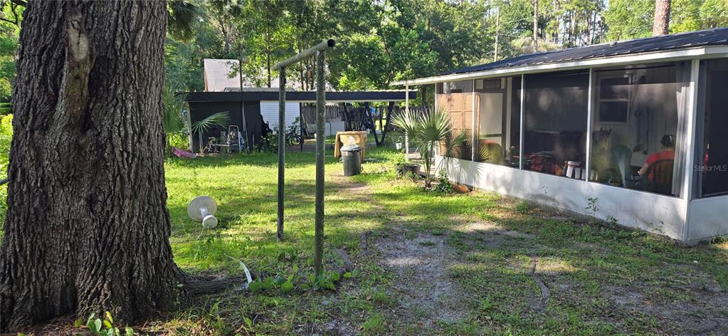 A large tree stands next to a house with a screened-in porch and yard — 45627 PENNSYLVANIA STREET, PAISLEY, FL