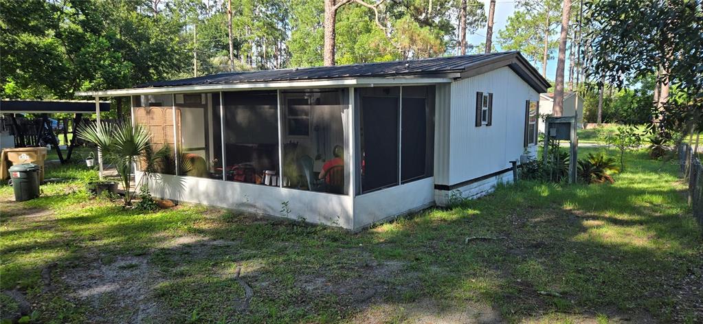 A mobile home with a screened-in porch sits on a grassy lot with trees — 45627 PENNSYLVANIA STREET, PAISLEY, FL