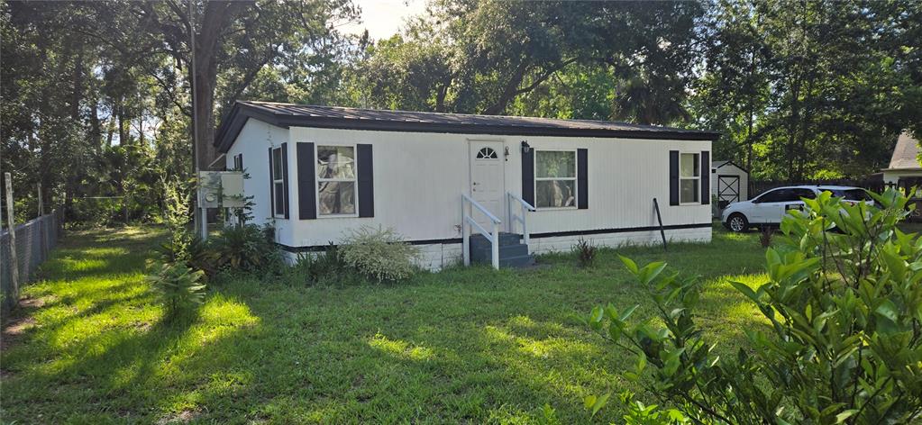 A single-story mobile home with white siding, black shutters, and a metal roof — 45627 PENNSYLVANIA STREET, PAISLEY, FL