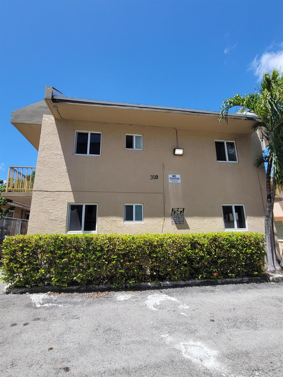 A two-story tan apartment building with a hedge and parking area in front — 310 NW 16th Avenue # 1, Miami FL 33125, MIAMI, FL
