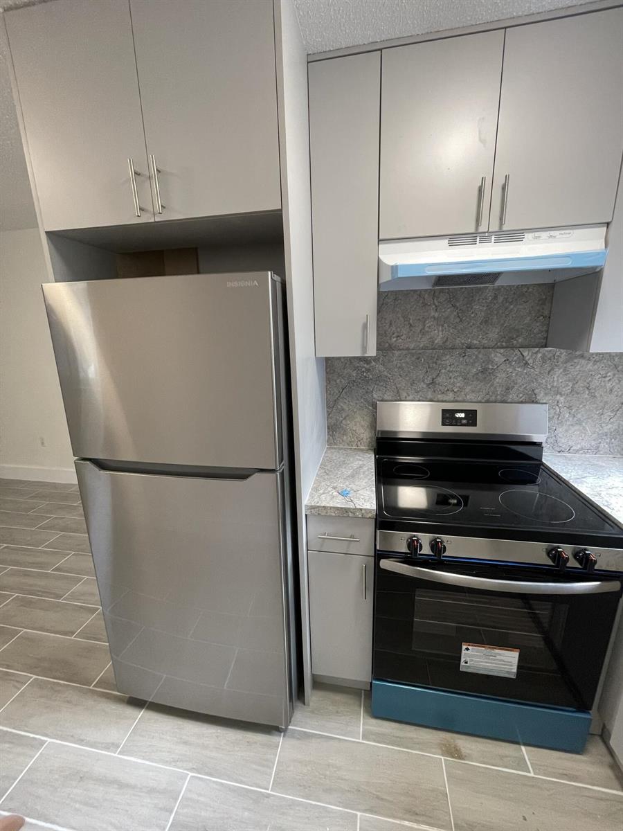 A kitchen features stainless steel appliances, light gray cabinets, and gray tile flooring — 310 NW 16th Avenue # 1, Miami FL 33125, MIAMI, FL