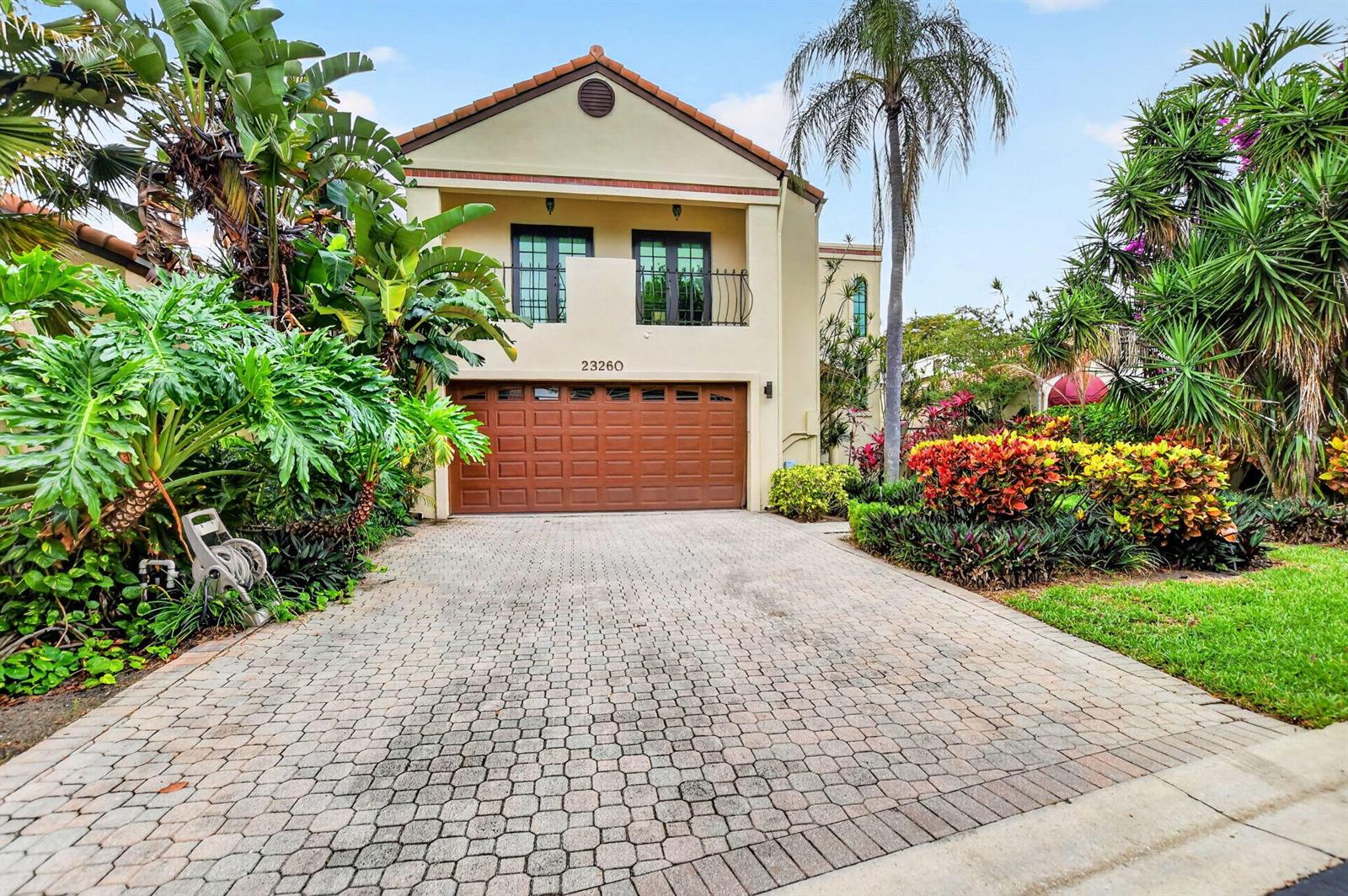 A two-story house with a brown garage door, a paved driveway, and lush tropical landscaping — 23260 Mirabella Circle N, Boca Raton FL 33433, BOCA RATON, FL