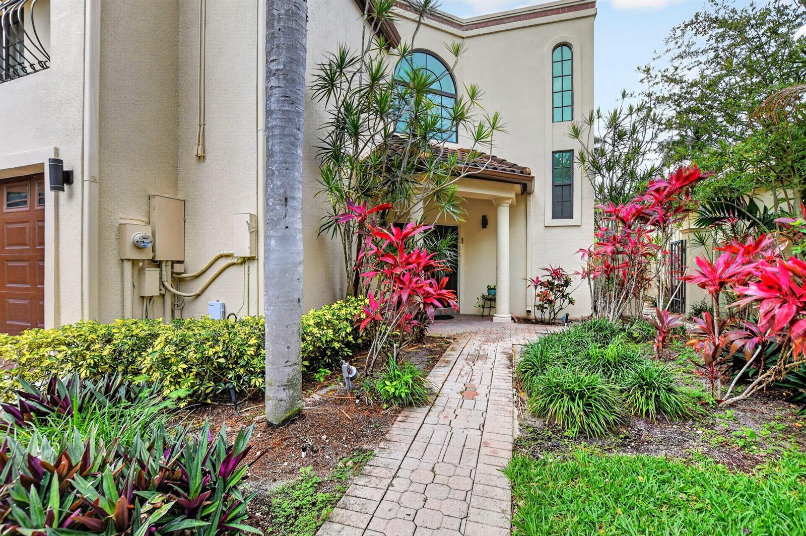 A brick walkway leads to the front entrance of a two-story stucco home with landscaping — 23260 Mirabella Circle N, Boca Raton FL 33433, BOCA RATON, FL