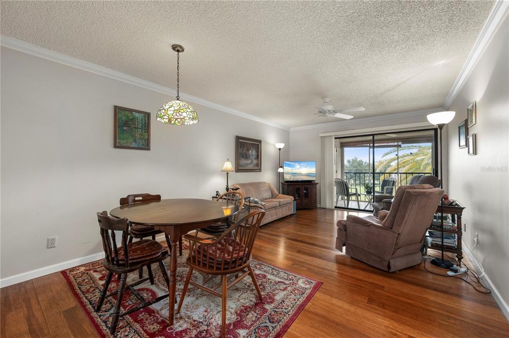 A dining area and living room with hardwood floors, a ceiling fan, and a balcony — 2395 HARBOR BOULEVARD UNIT 310, PORT CHARLOTTE, FL