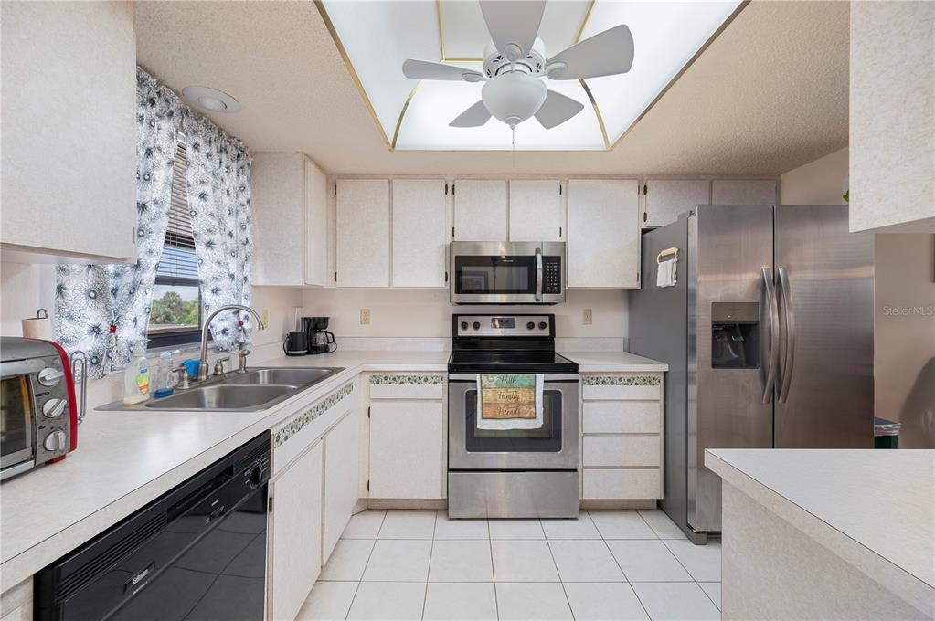 A kitchen with white cabinets, stainless steel appliances, a tile floor, and a ceiling fan — 2395 HARBOR BOULEVARD UNIT 310, PORT CHARLOTTE, FL