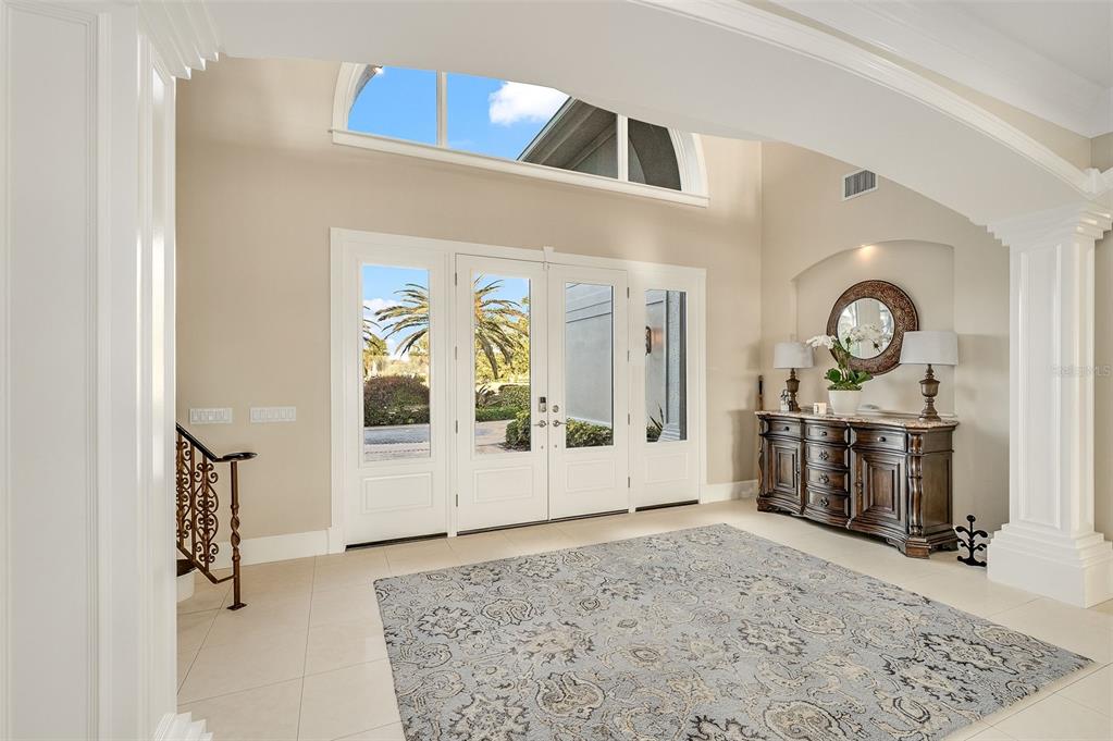 A bright foyer features a large area rug, a dark wood console table, and double doors — 281 LANSING ISLAND DRIVE, INDIAN HARBOUR BEACH, FL