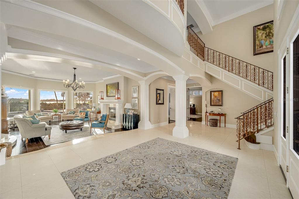 A spacious foyer with tile flooring leads to a living room and a grand staircase — 281 LANSING ISLAND DRIVE, INDIAN HARBOUR BEACH, FL