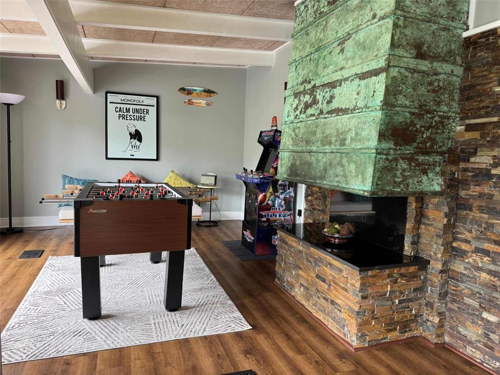 A game room features a foosball table, an arcade machine, and a large copper-hooded fireplace — 3012 GRAND VIEW AVENUE, CLEARWATER, FL