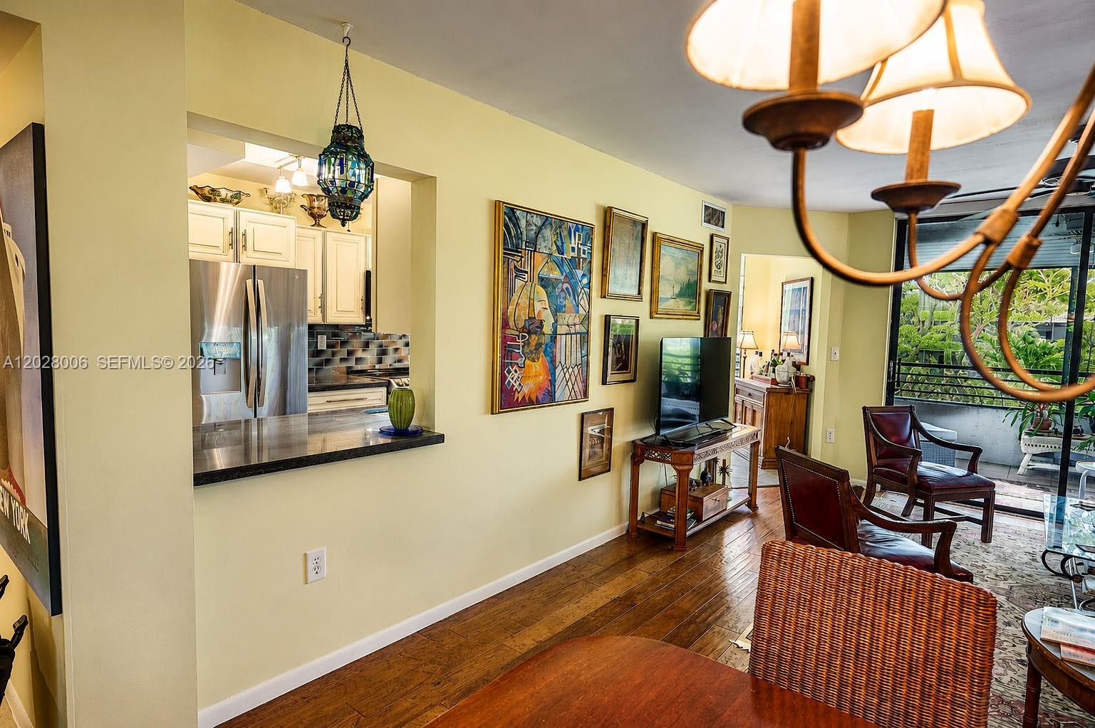 A living and dining area features hardwood floors, a kitchen pass-through, and a balcony view — 1450 Sheridan St # 13, Hollywood FL 33020, HOLLYWOOD, FL