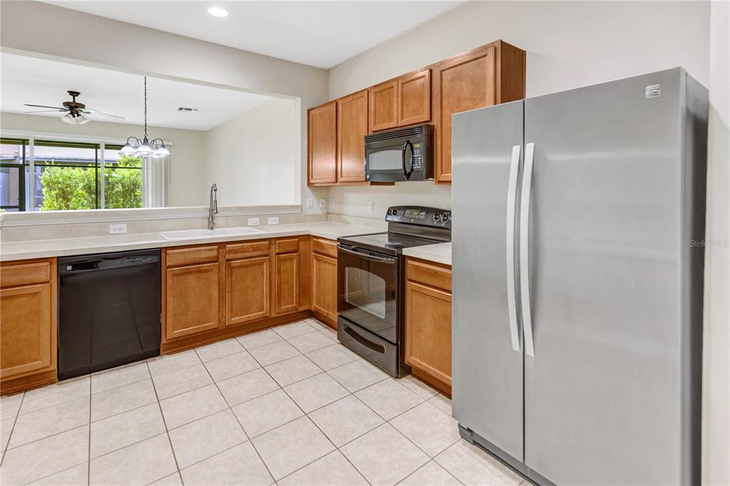 A kitchen features wood cabinets, stainless steel appliances, a tile floor, and a breakfast bar — 10135 POST HARVEST DRIVE, RIVERVIEW, FL