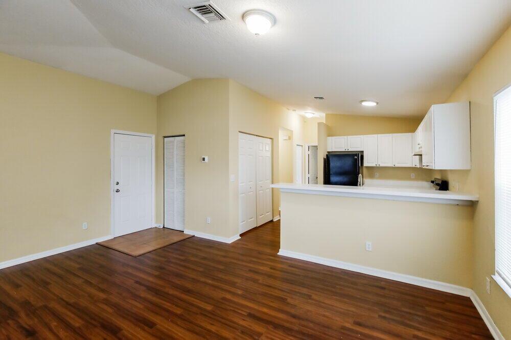 An open-concept living area features wood-look flooring, beige walls, and a kitchen with white cabinets — HOLLYWOOD, FL