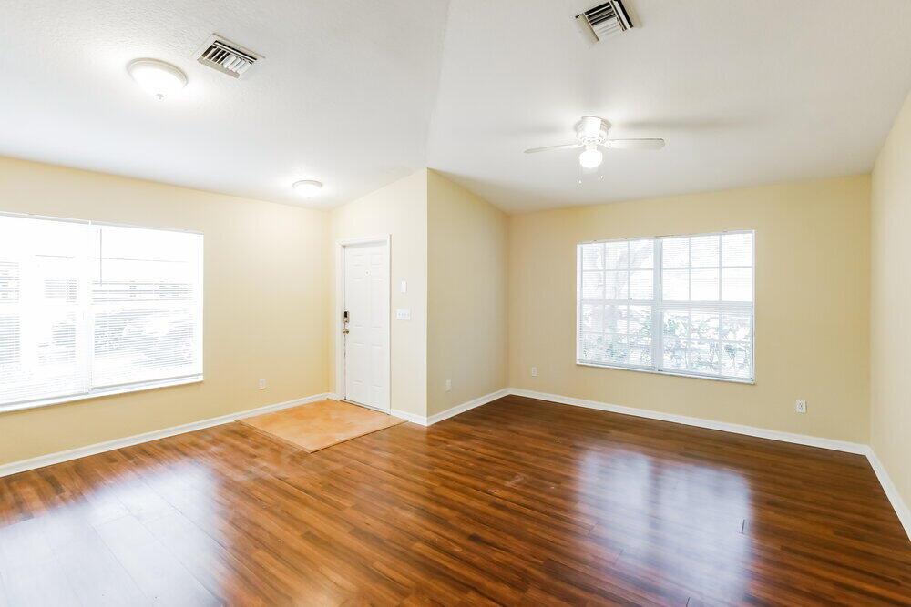 An empty living room with light yellow walls, wood-look flooring, and a ceiling fan — HOLLYWOOD, FL