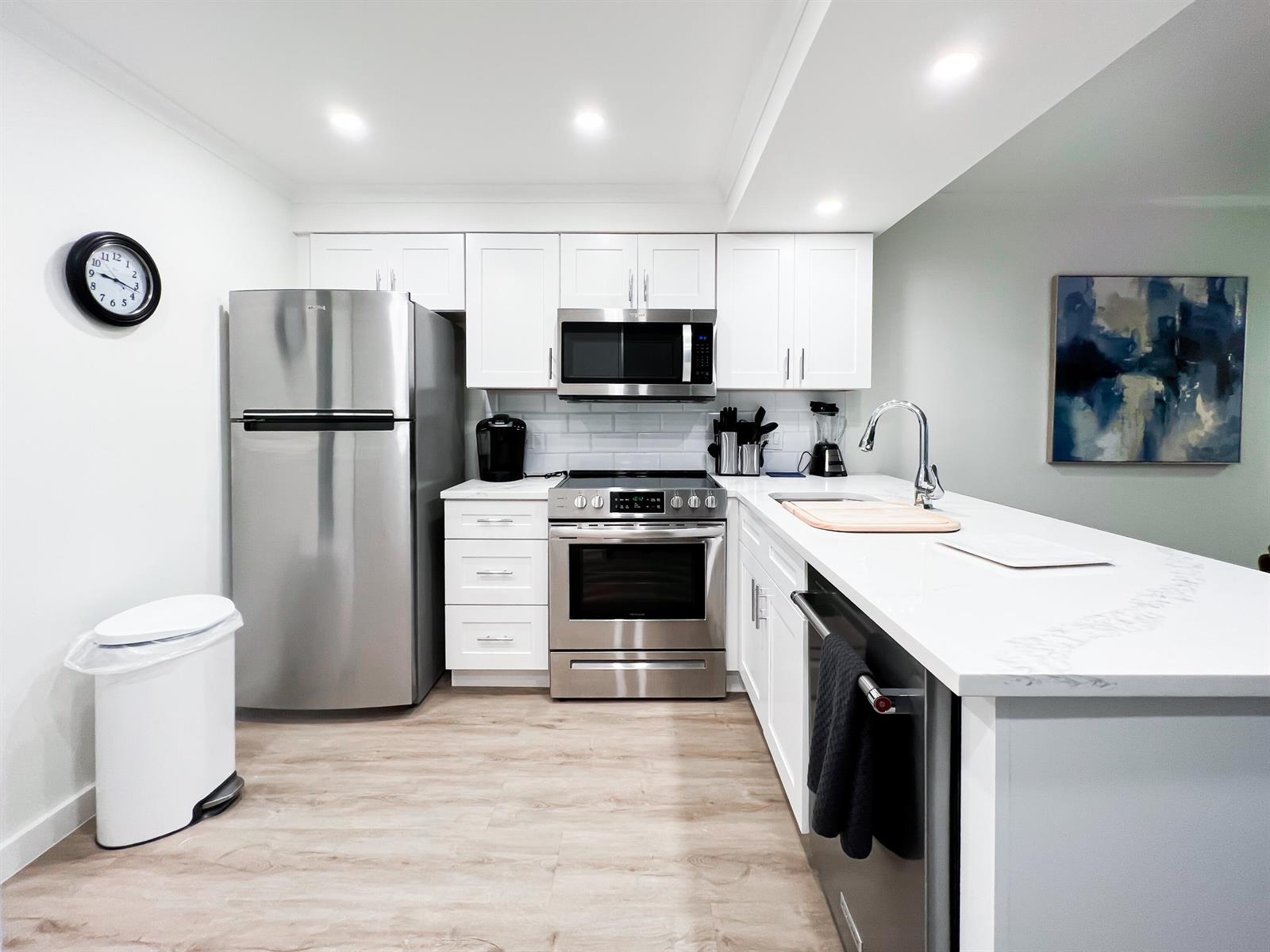 A modern kitchen features white cabinets, stainless steel appliances, and a white quartz countertop island — 1605 S Us Highway 1 # C103, Jupiter FL 33477, JUPITER, FL