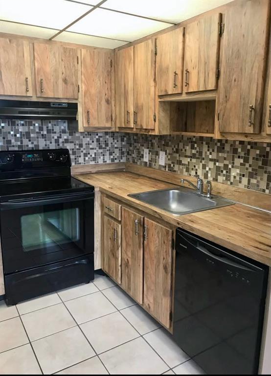 A kitchen with wood cabinets, a black stove and dishwasher, and a mosaic tile backsplash — 2565 OAK PARK WAY UNIT 213, ORLANDO, FL