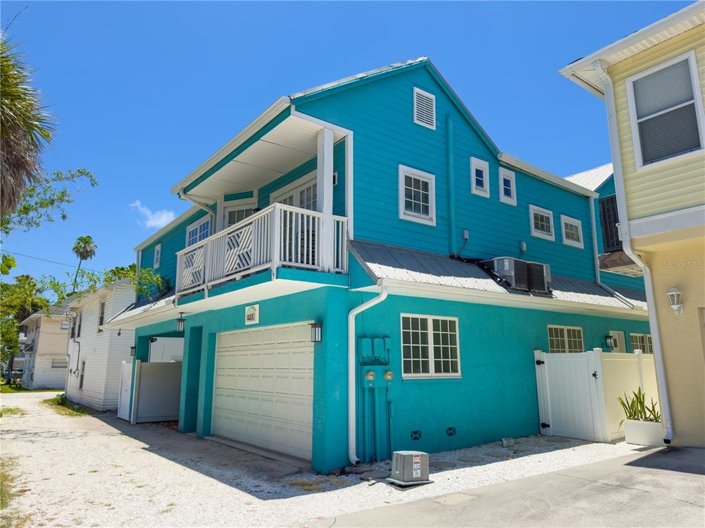 A bright turquoise two-story house with a white garage door and a second-floor balcony — 105 21ST AVENUE, ST PETE BEACH, FL