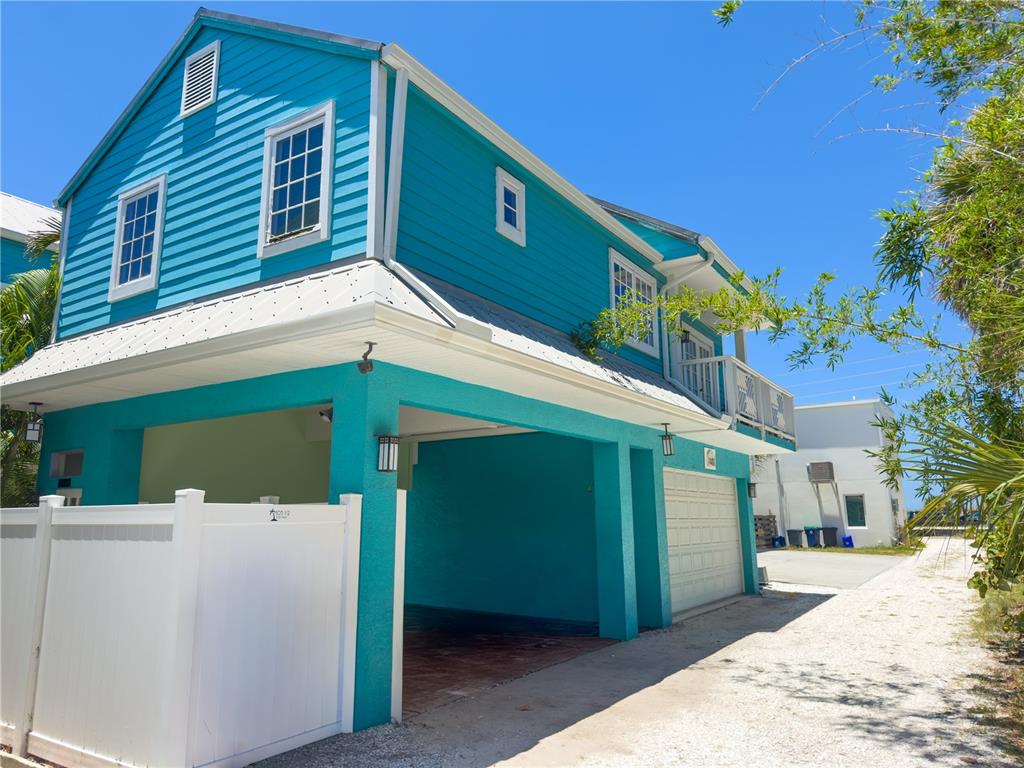 A two-story teal house with a covered parking area and a white vinyl fence — 105 21ST AVENUE, ST PETE BEACH, FL