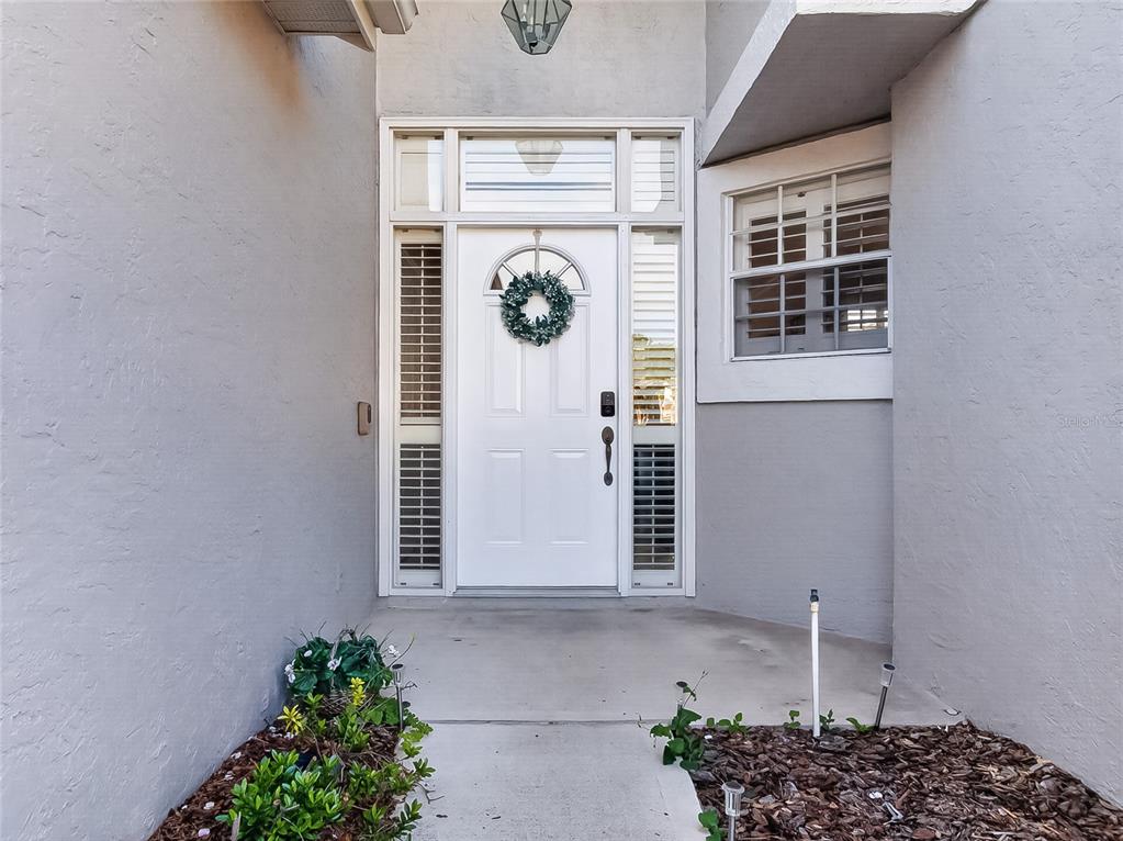 The exterior view shows a white front door with a wreath and sidelight windows — 14435 WINDCHIME LANE, ORLANDO, FL