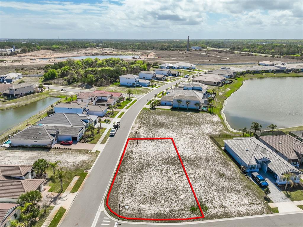 An aerial view shows a vacant residential lot outlined in red next to a lake — 1 DEL PALMA DRIVE, PALM COAST, FL