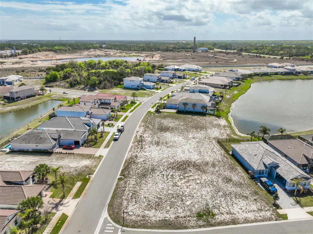 An aerial view shows a vacant residential lot situated between houses and a lake — 1 DEL PALMA DRIVE, PALM COAST, FL