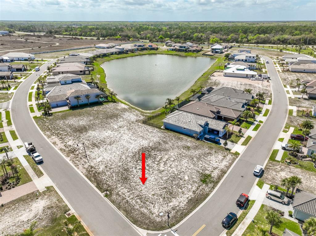 An aerial view shows a vacant residential lot situated between two curved streets and a pond — 1 DEL PALMA DRIVE, PALM COAST, FL