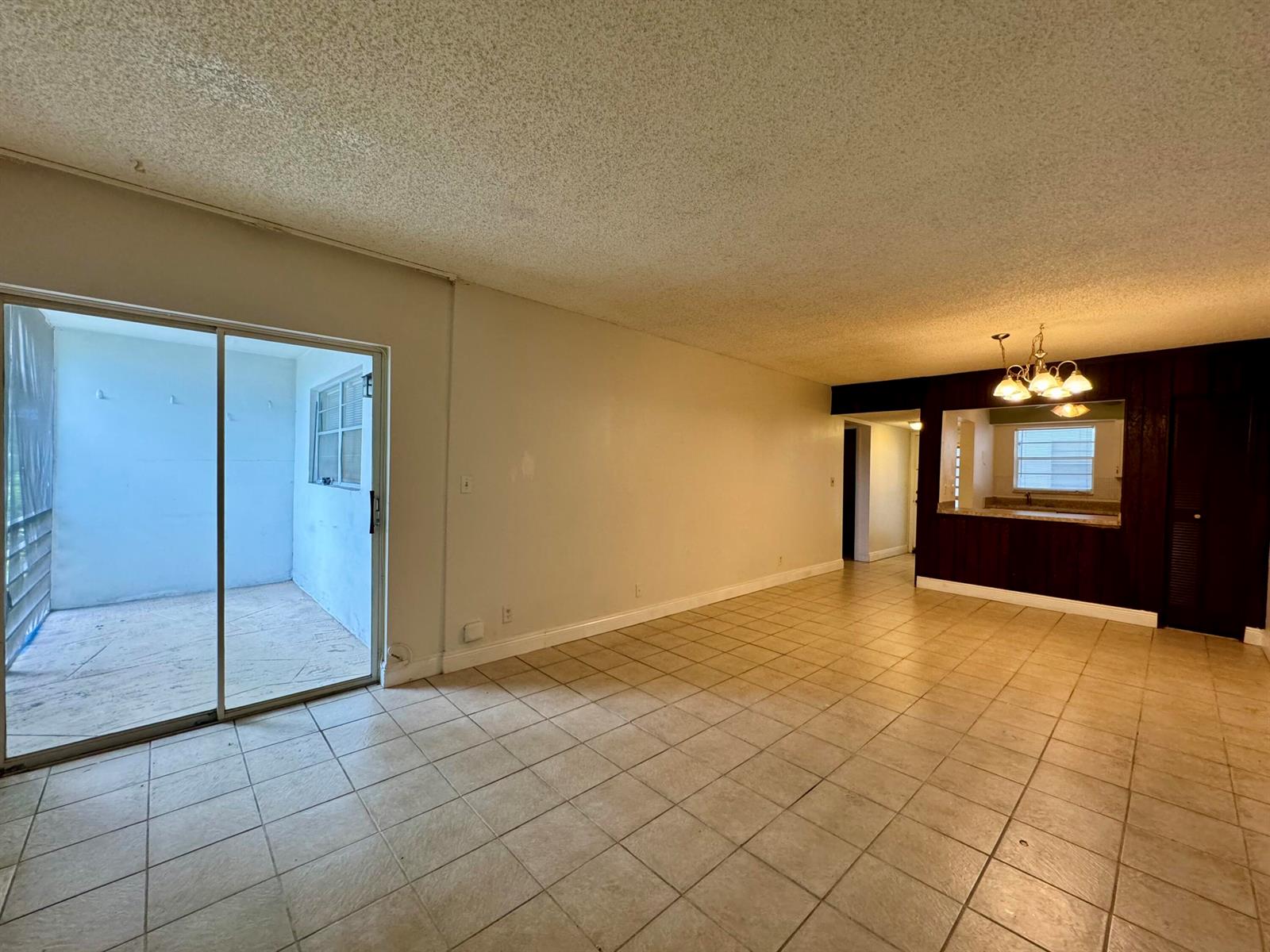 An open-concept living area features tile flooring, a sliding glass door, and a kitchen pass-through — 6505 Winfield Boulevard # 45, Margate FL 33063, MARGATE, FL