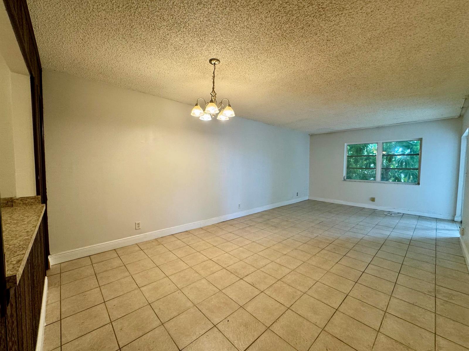 An empty dining room with beige tile flooring, a popcorn ceiling, and a hanging light fixture — 6505 Winfield Boulevard # 45, Margate FL 33063, MARGATE, FL