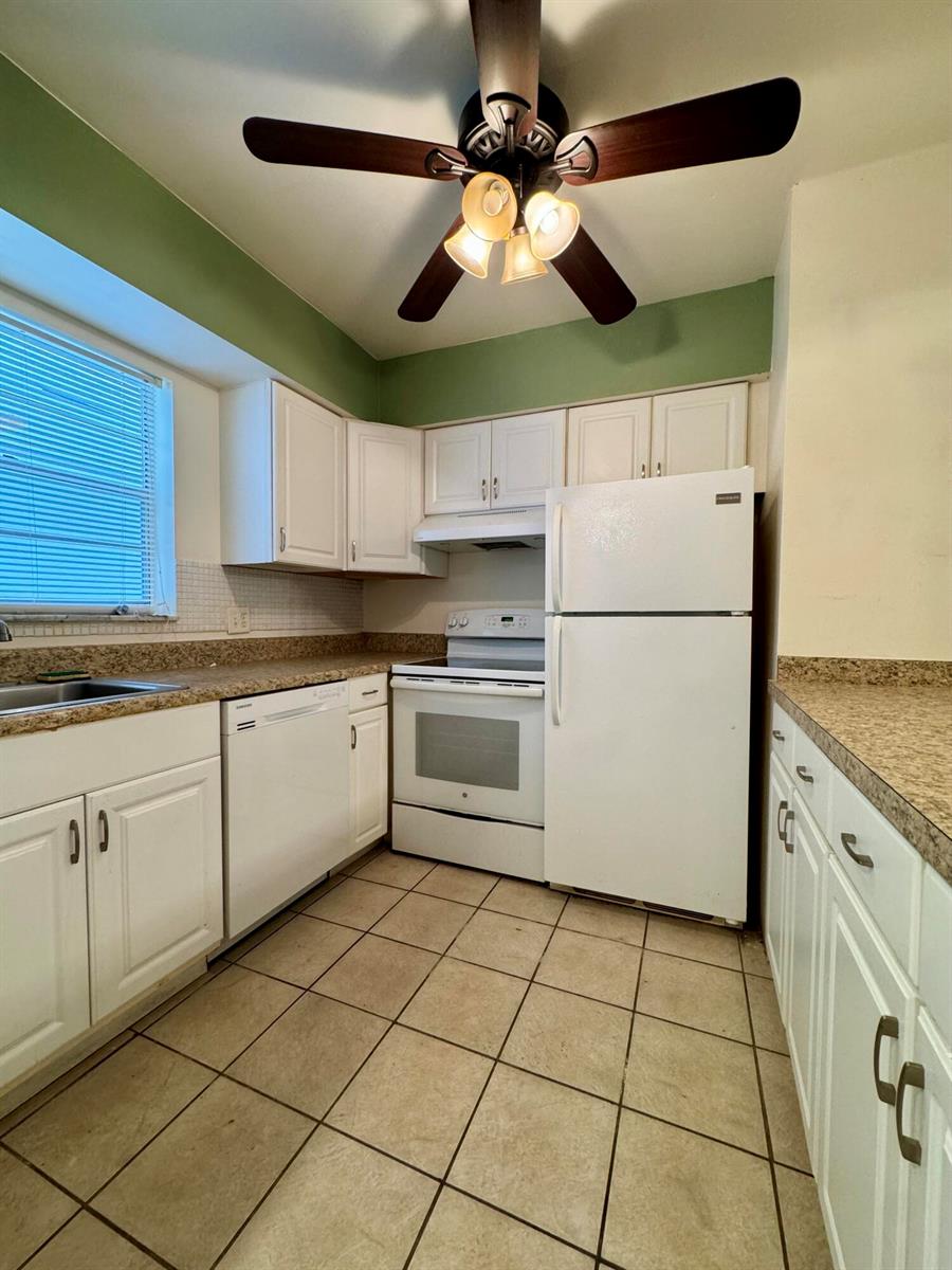 A kitchen features white cabinets, white appliances, tan countertops, and tiled flooring — 6505 Winfield Boulevard # 45, Margate FL 33063, MARGATE, FL