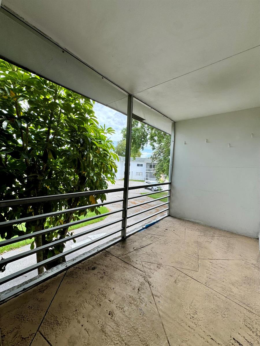 A screened-in balcony with a concrete floor overlooks a parking lot and trees — 6505 Winfield Boulevard # 45, Margate FL 33063, MARGATE, FL