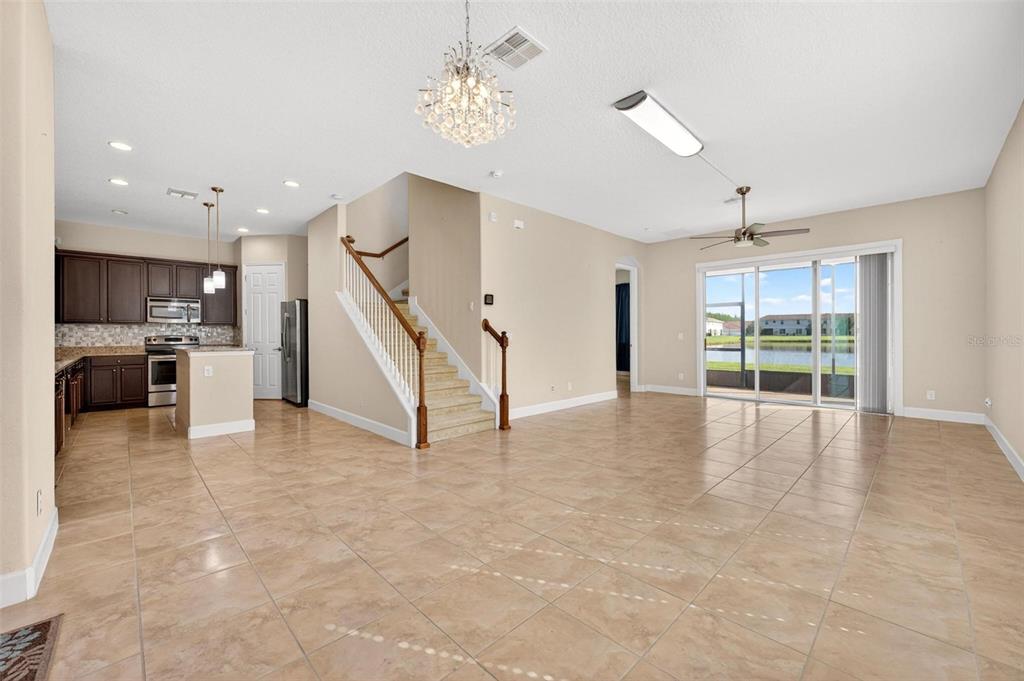 An open-concept living area features tile flooring, a staircase, and a kitchen with dark cabinets — 2101 PAINTER LANE, KISSIMMEE, FL