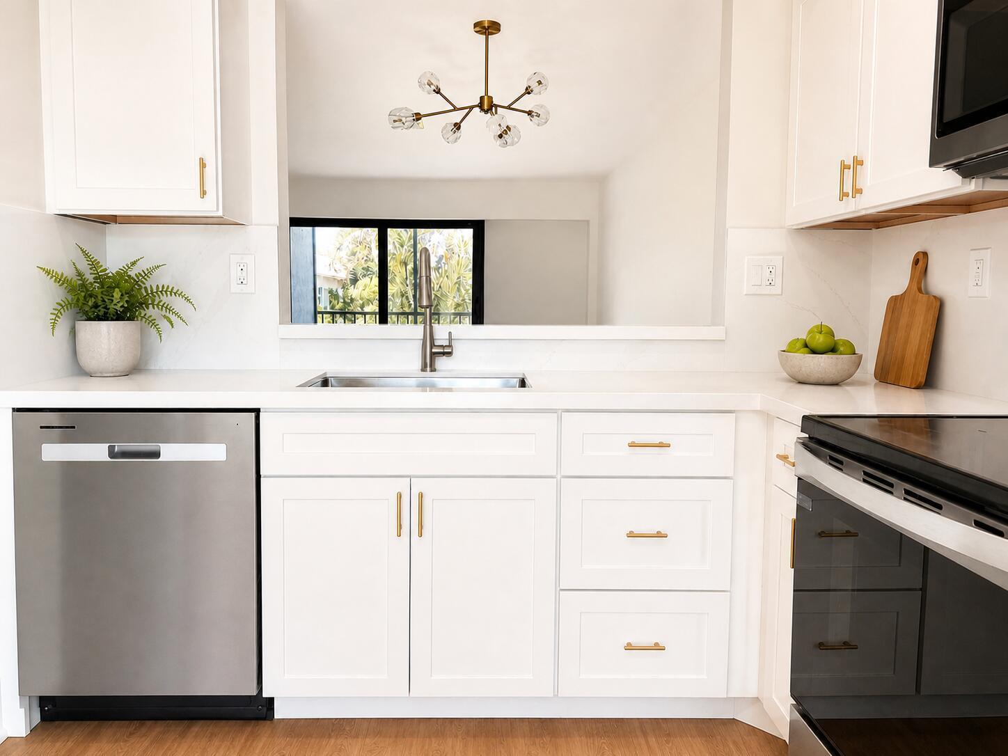 A modern kitchen features white cabinets, stainless steel appliances, gold hardware, and a pass-through window — 3275 Frederick Boulevard # 17, Delray Beach FL 33483, DELRAY BEACH, FL
