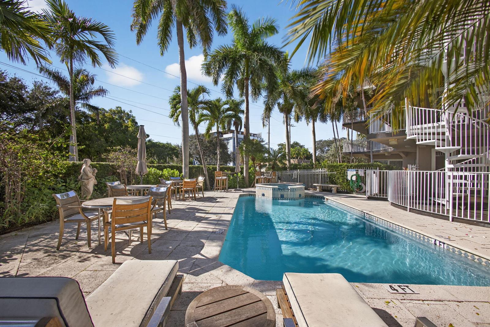 A rectangular swimming pool with an attached hot tub sits on a stone patio — 129 S Golfview Road # 7, FL 33460, FL