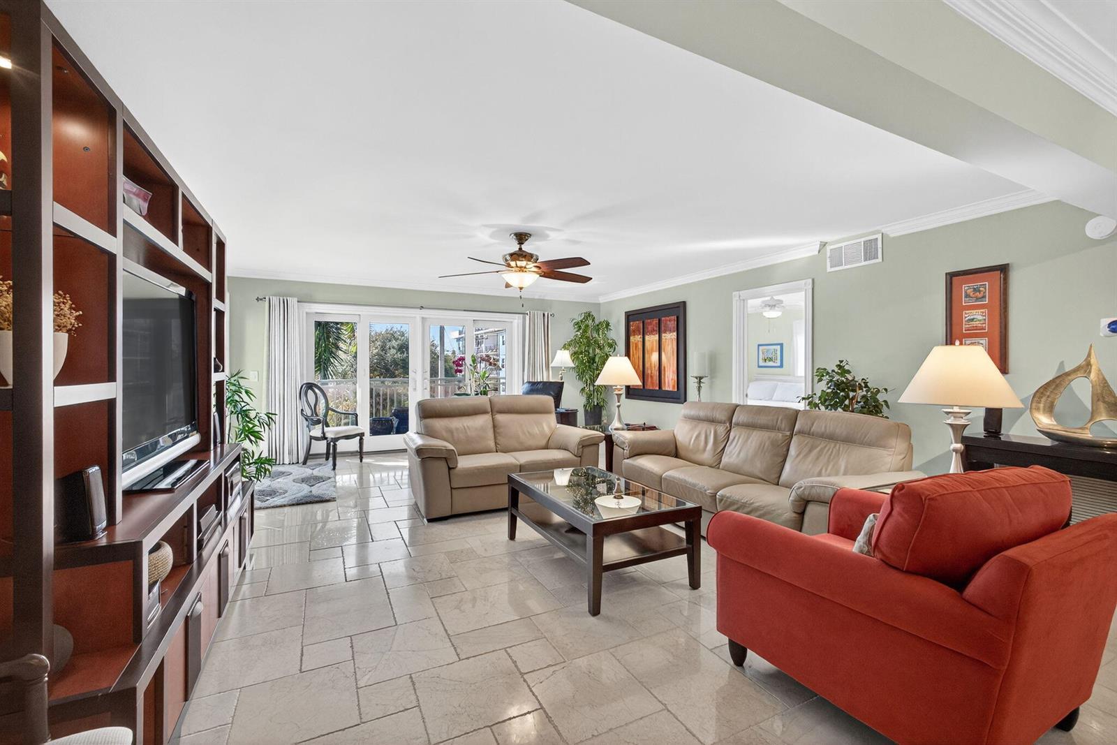 A living room features light tile flooring, a large entertainment center, and neutral leather sofas — 129 S Golfview Road # 7, FL 33460, FL