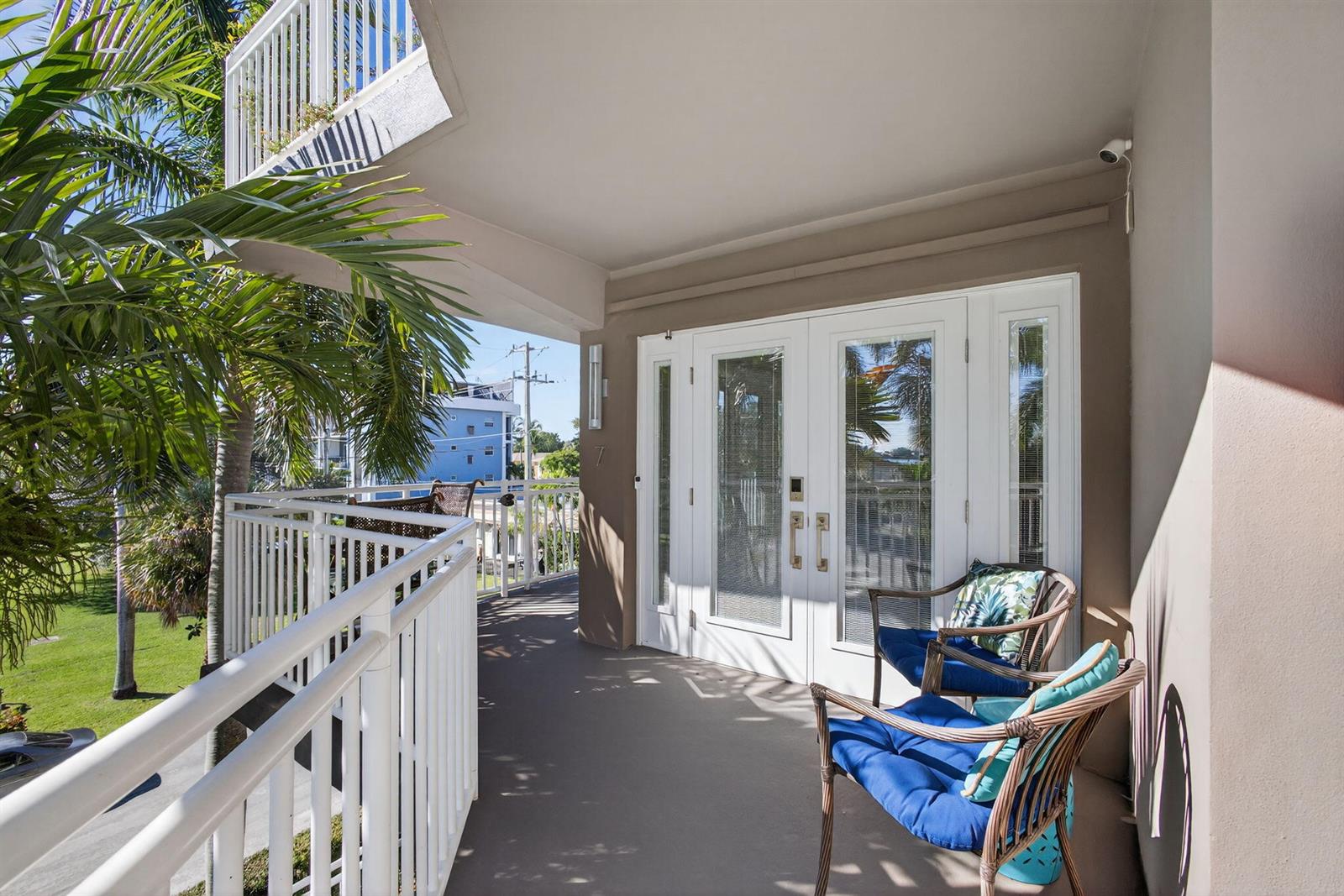 A balcony features white railings, two chairs with blue cushions, and glass double doors — 129 S Golfview Road # 7, FL 33460, FL