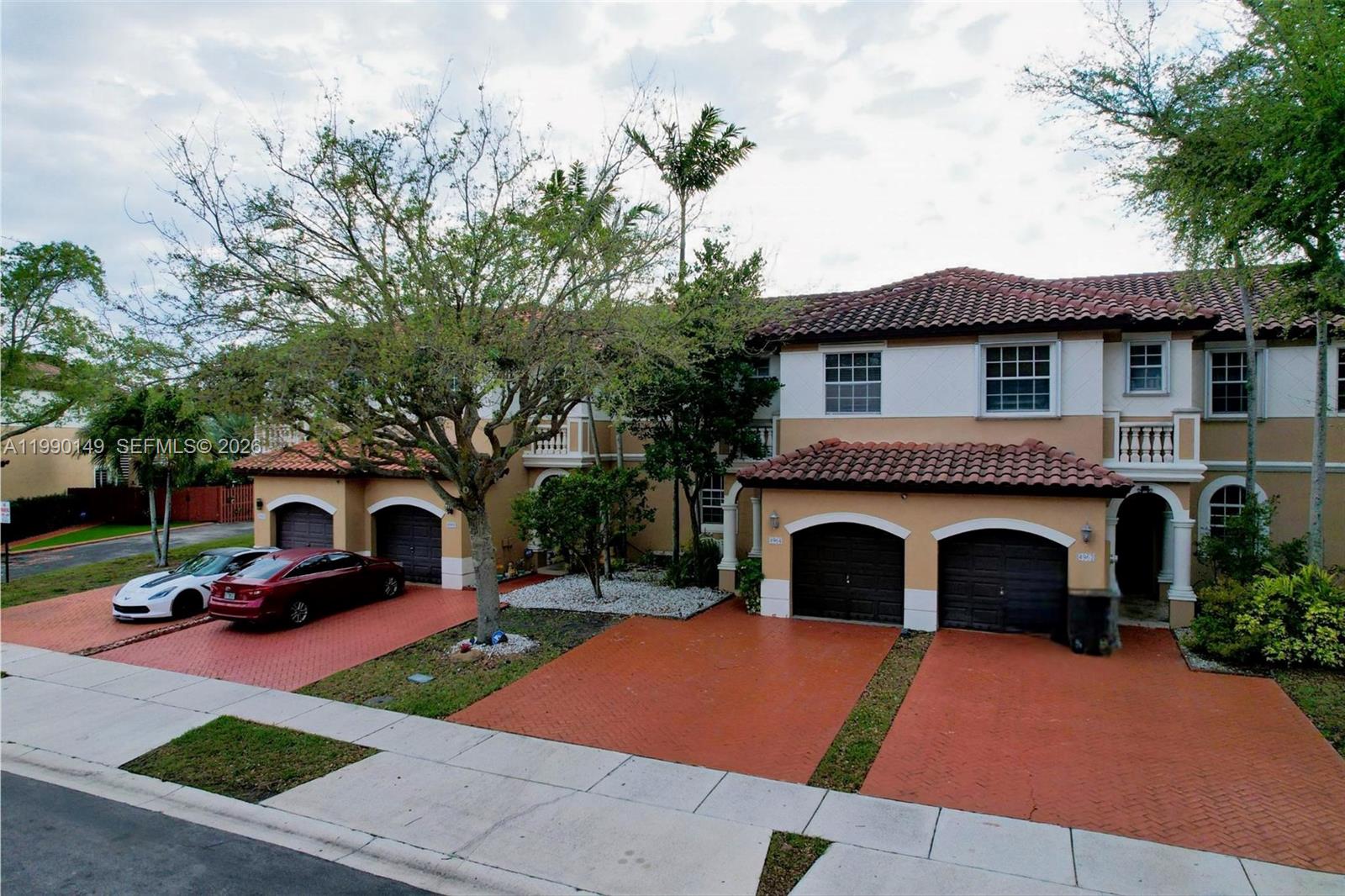 A two-story townhouse complex features red-tiled roofs, tan stucco walls, and paved driveways — 4964 SW 128th Ave, Miramar FL 33027, MIRAMAR, FL