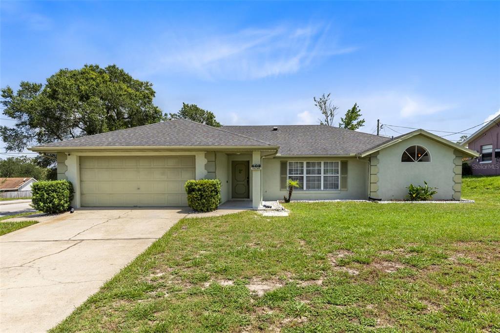 A single-story house with a light green exterior, a two-car garage, and a front lawn — 602 VICKSBURG STREET, DELTONA, FL