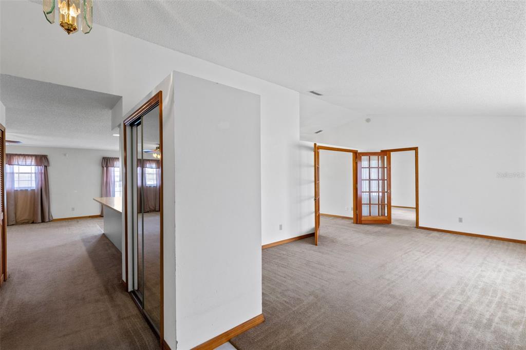 An interior view of a carpeted room featuring a mirrored closet and French doors — 602 VICKSBURG STREET, DELTONA, FL