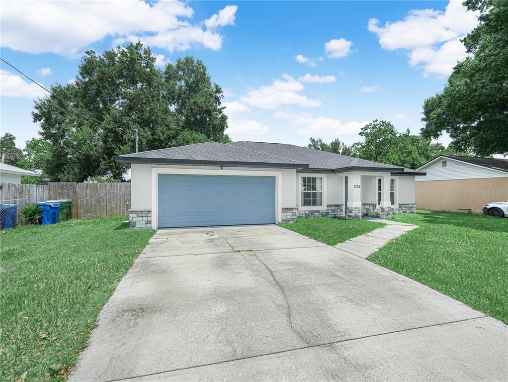 A single-story house with a blue garage door, stone accents, and a concrete driveway — 1705 SANDALWOOD CIRCLE SW, WINTER HAVEN, FL