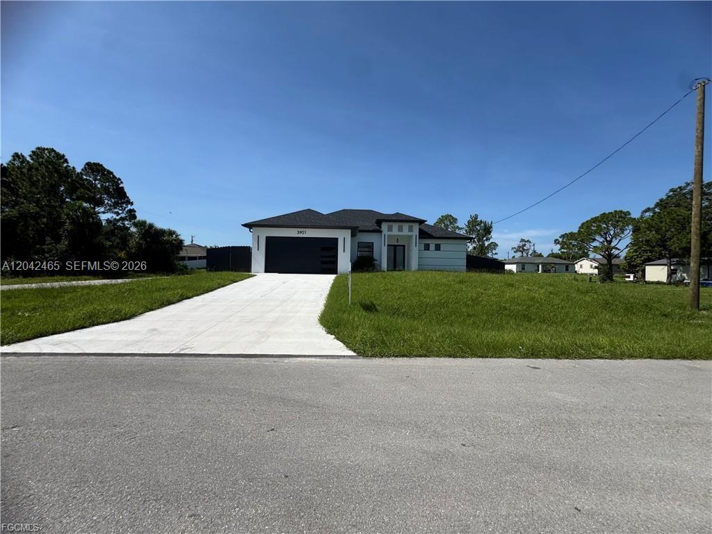 A single-story house with a white exterior, a dark garage door, and a concrete driveway — 3901 3rd ST SW, Lehigh Acres FL 33976, LEHIGH ACRES, FL